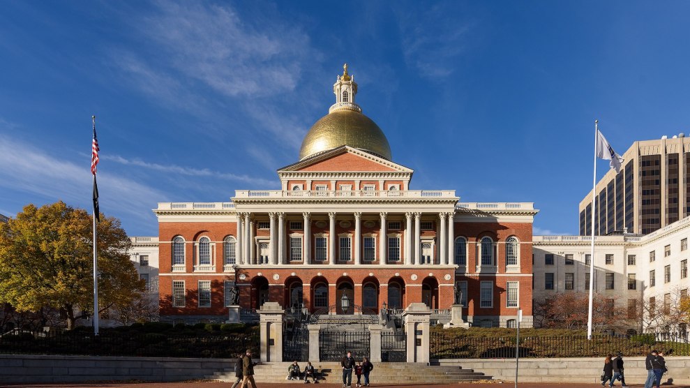 The Massachusetts State House, which is a brick and gold building, with a blue sky behind it.