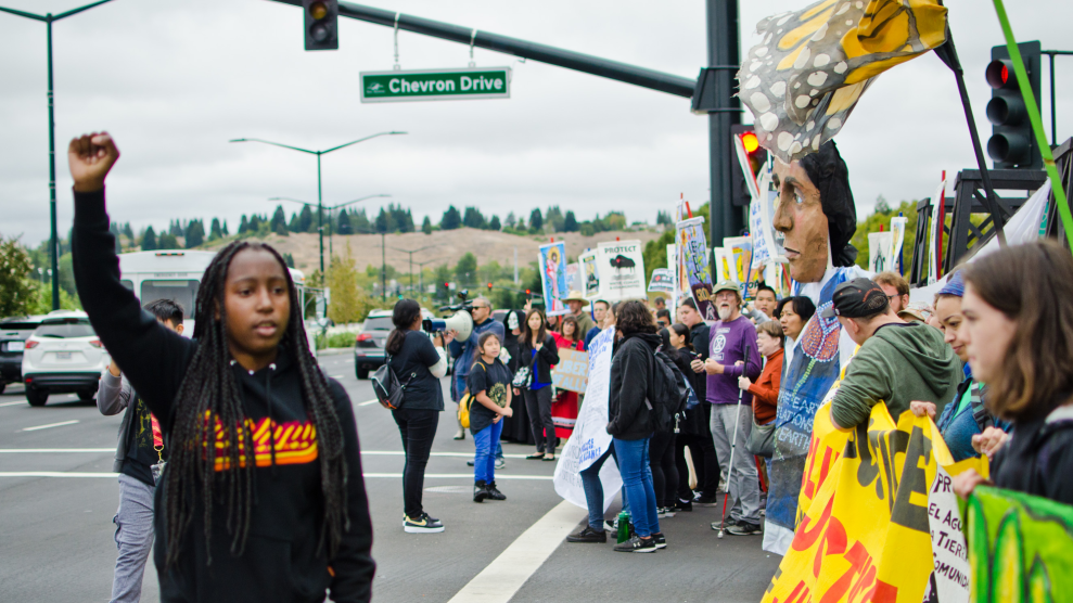 A climate striker with Youth vs. Apocalypse rallies the crowd outside Chevron's headquarters.