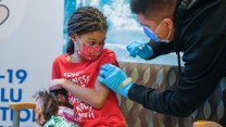 Amelle Samuel, 7, holding her doll, receives a shot of COVID-19 vaccine during one in a series of free COVID-19 and flu vaccination clinics held by Children's Hospital Los Angeles, in Arcadia, California, January 8, 2022.