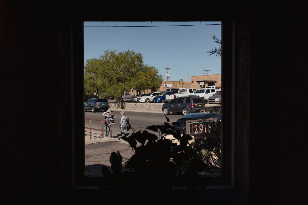 Pro-Life activists are seen through the window as they protest outside the Las Cruces Women's Health Organization.