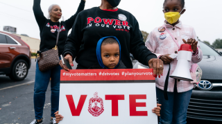 A young boy holds a sign during a rally advocating for early voting and voting rights on Sunday, October 30, 2022 in Decatur, GA.