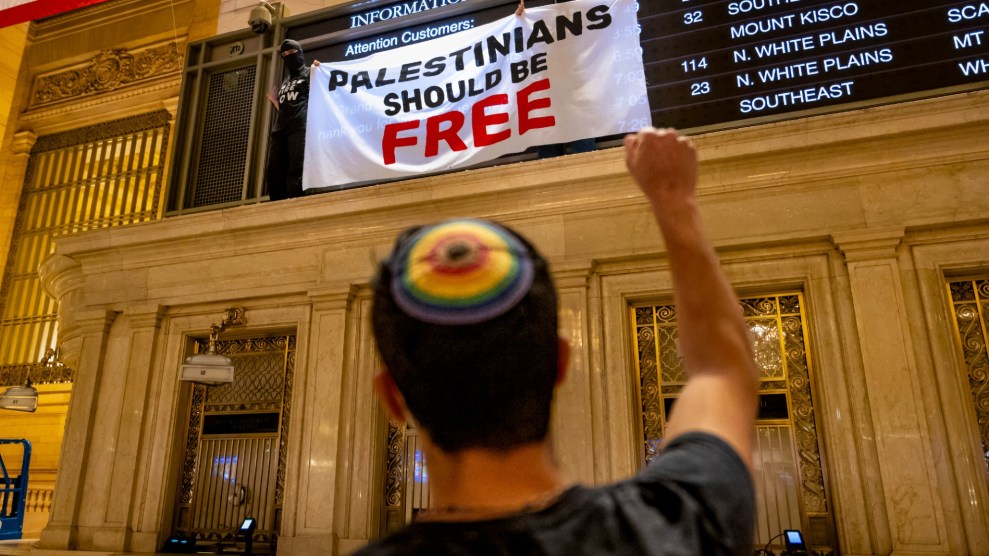 A person with a rainbow yarmulke raises their right fist to a banner that says "Palestinians Should Be Free."