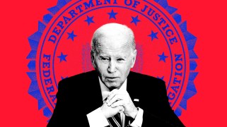 President Joe Biden sits in front of a red background. There is a large, blue U.S. Department of Justice FBI seal on the background behind him.