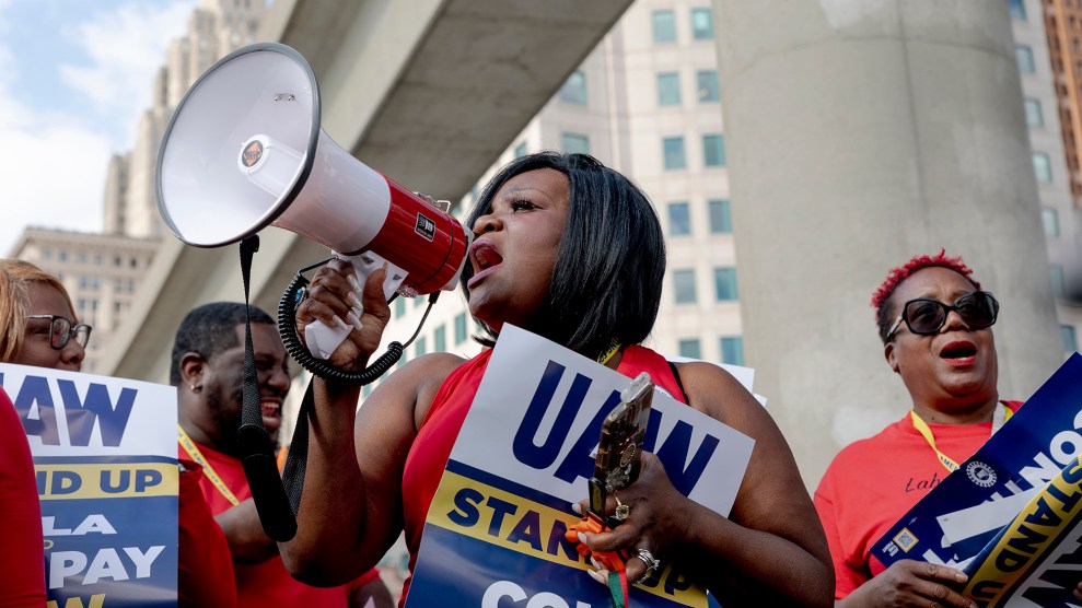 Woman with bullhorn holding a UAW protest sign.