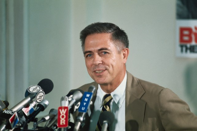 Smiling man talking into microphones.