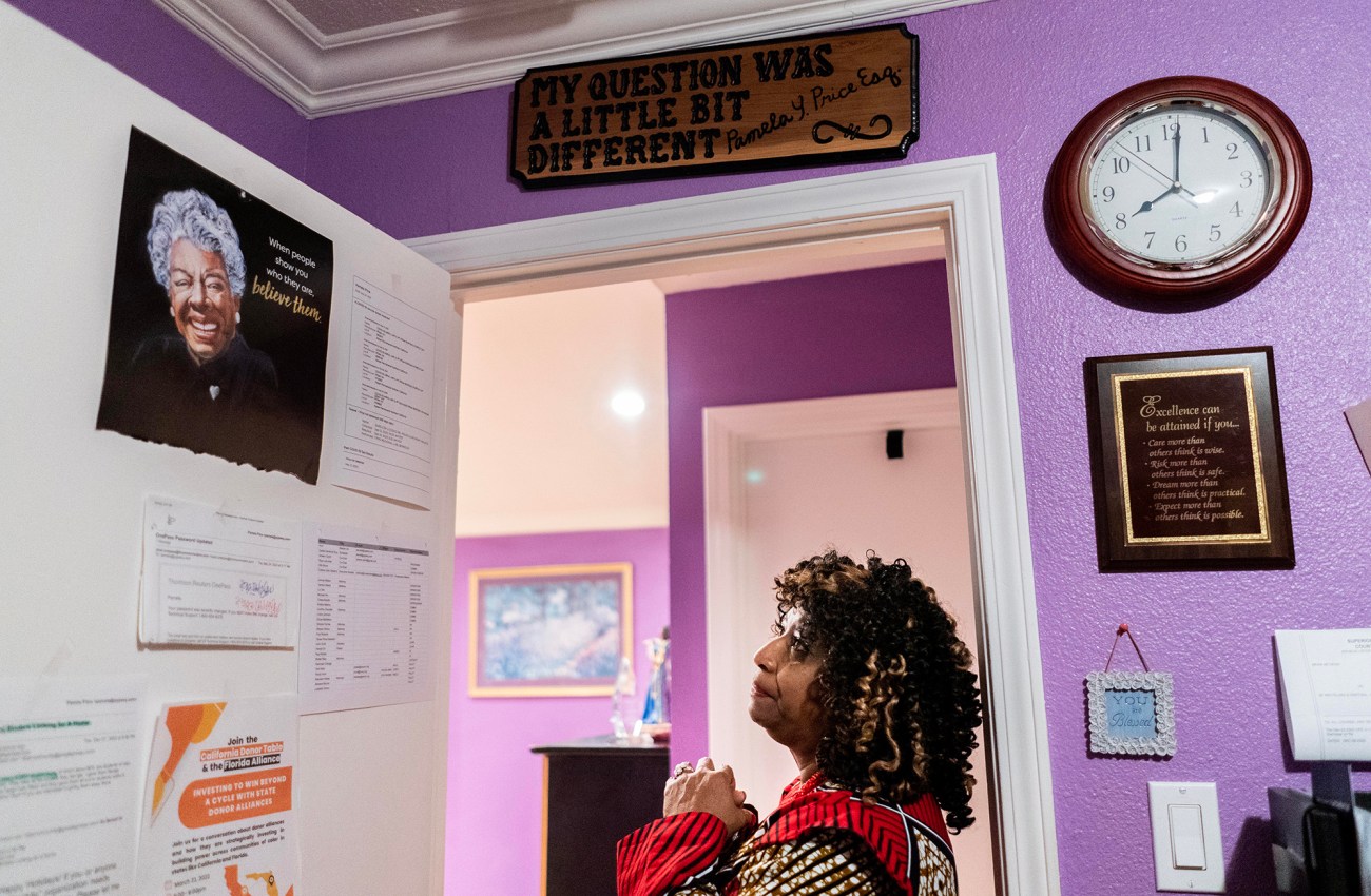 Woman standing in doorway to an office, looking up at a poster.