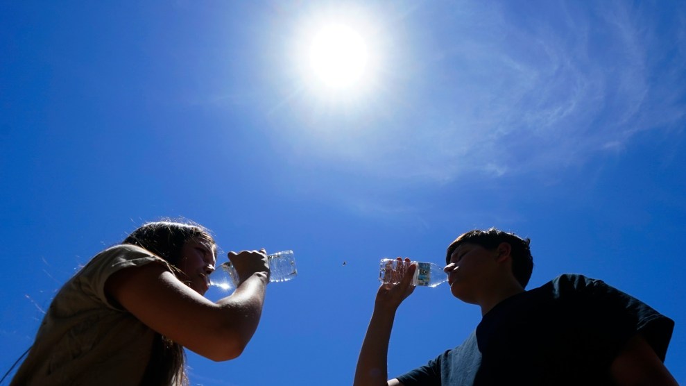 Two children stand in front of the sun and blue sky.