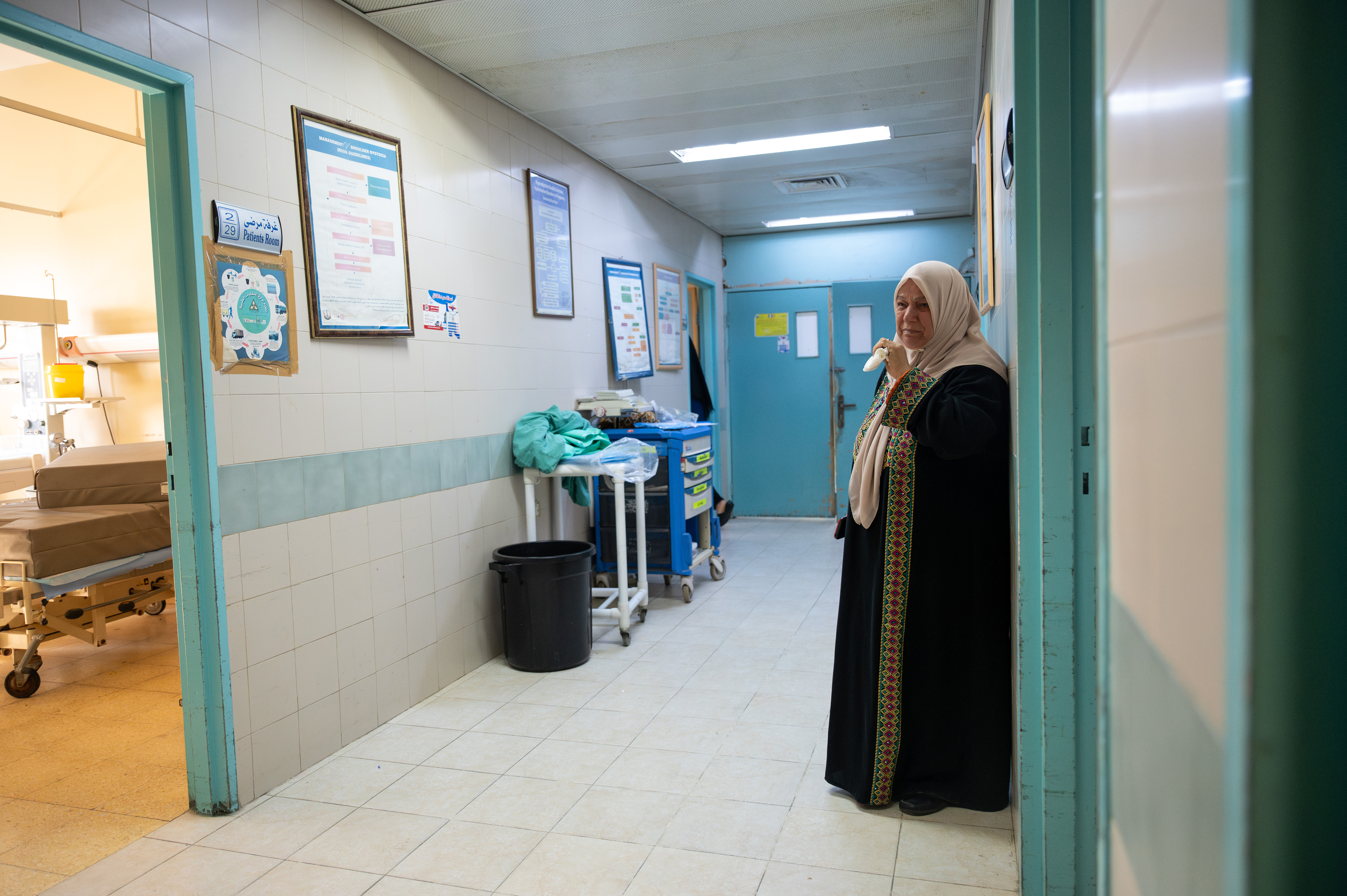 A woman standing alone in a hospital hallway, crying.
