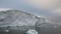 A view of the doomsday glacier in Antarctica, next to a body of water.