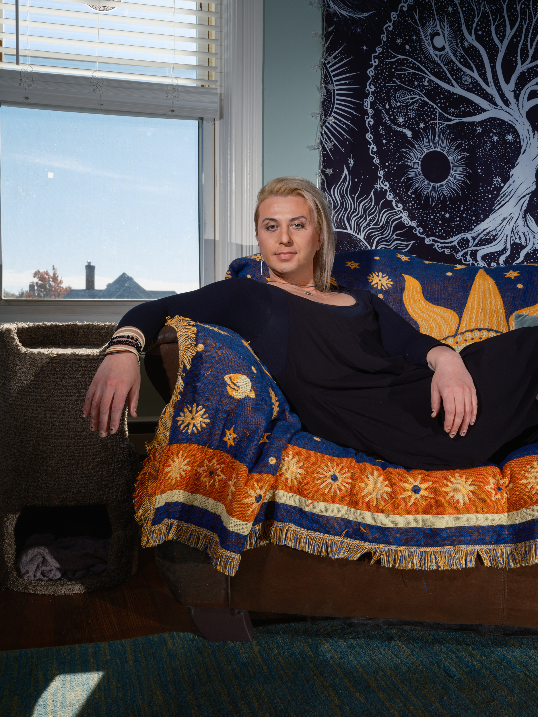 Blond person laying on couch with their arm drapped over the armrest.