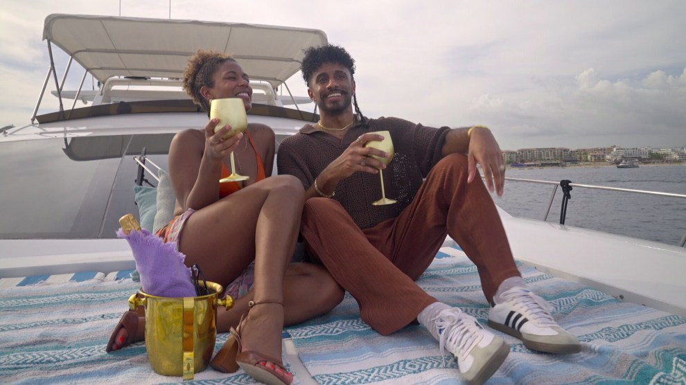 A couple, recently engaged, sits on the bow of a boat