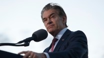 Dr. Oz, a man with light skin, standing on a stage in a suit in front of a microphone