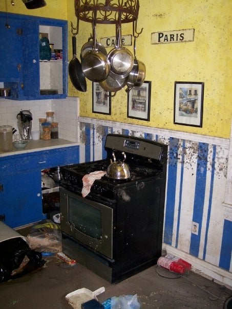 Kitchen with yellow and blue walls caked in grime