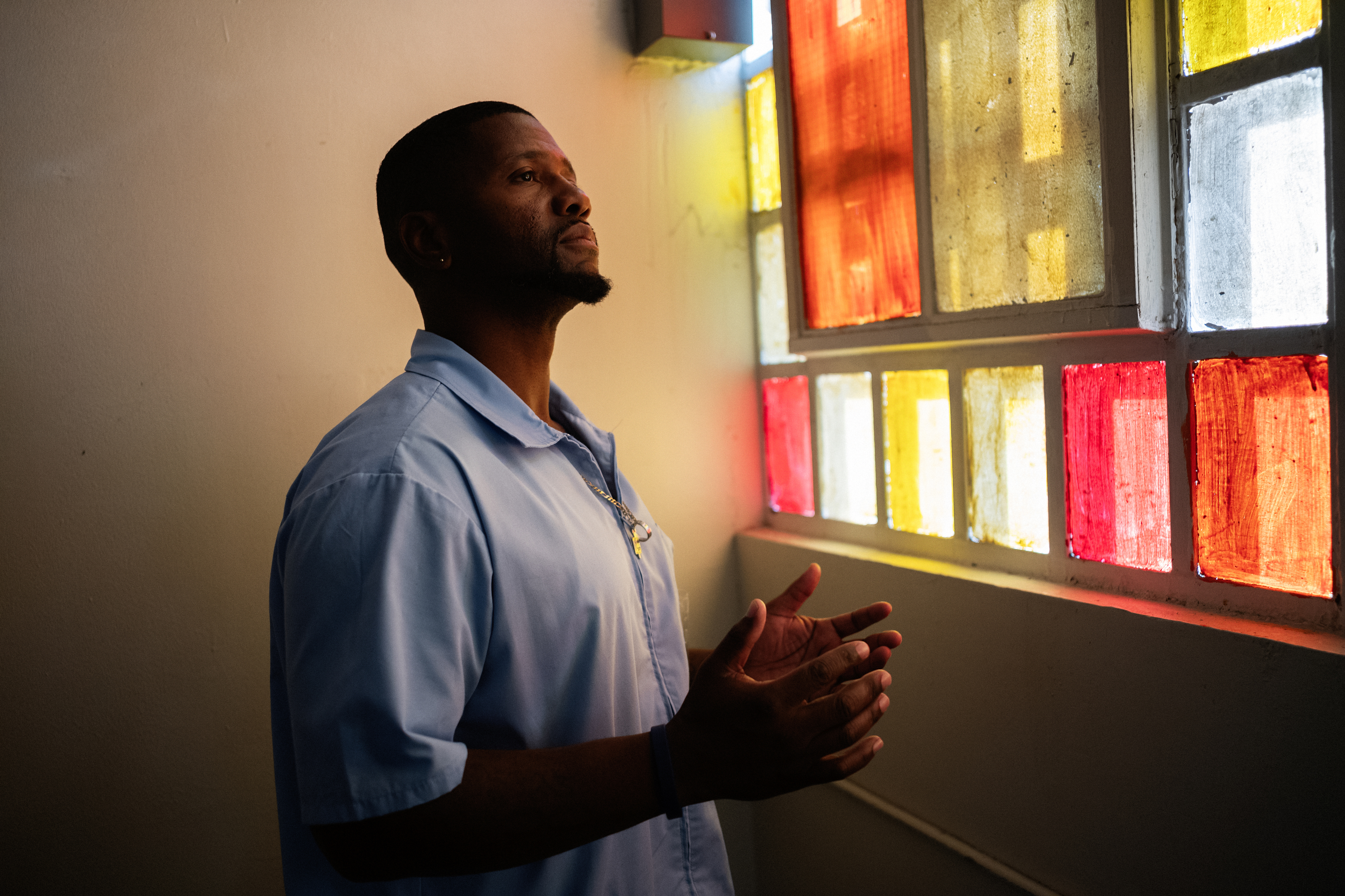 Portrait of a man standing by stained glass window.