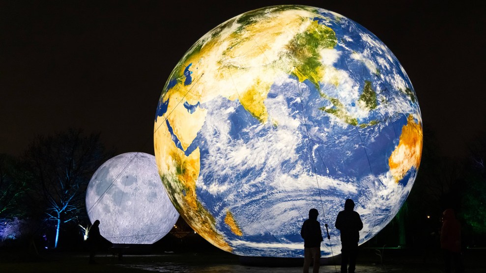 Two silhouetted figures stand in front of a large, illuminated globe.