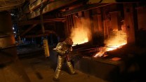 A smelter works in silvery, heat-protection suit in a smelting factory.