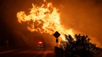 Fire flares near a yeild sign in the darkness.