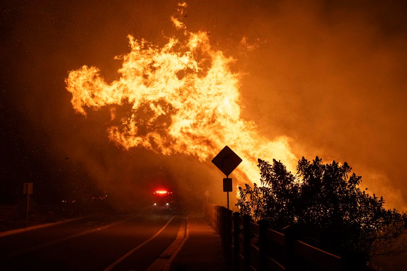 Fire flares near a yeild sign in the darkness.