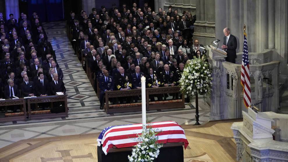 Steve Ford, Gerald Ford's son, eulogizes Jimmy Carter, with Carter's flag-covered casket in the foreground