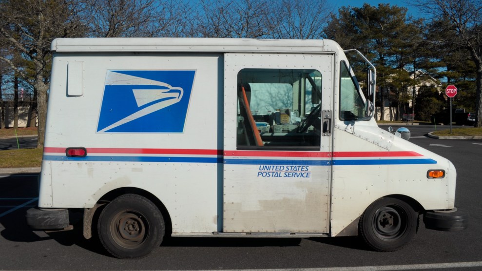 A United States Postal Service truck shown in a side view on the road.