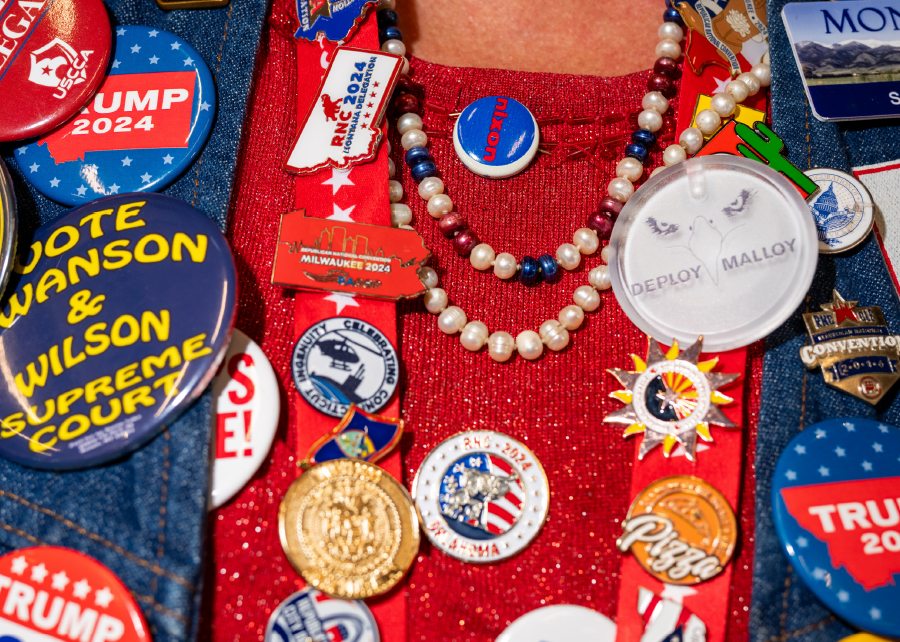 A close-up of an older woman attending the RNC, who is clearly an avid Trump supporter; she is adorned in countless conservative political buttons, pins, and beaded necklaces.