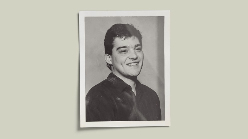 A black-and-white vintage photograph of a young man with short dark hair, wearing a collared shirt. He is smiling. The photo is set against a pale green background.