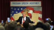 Trump speaks in front of an image of the Constitution and a sign reading "Freedom of Speech and Assembly"