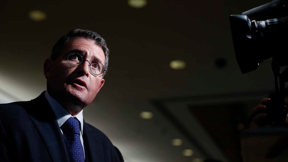 A white man wearing a blue tie and glasses.