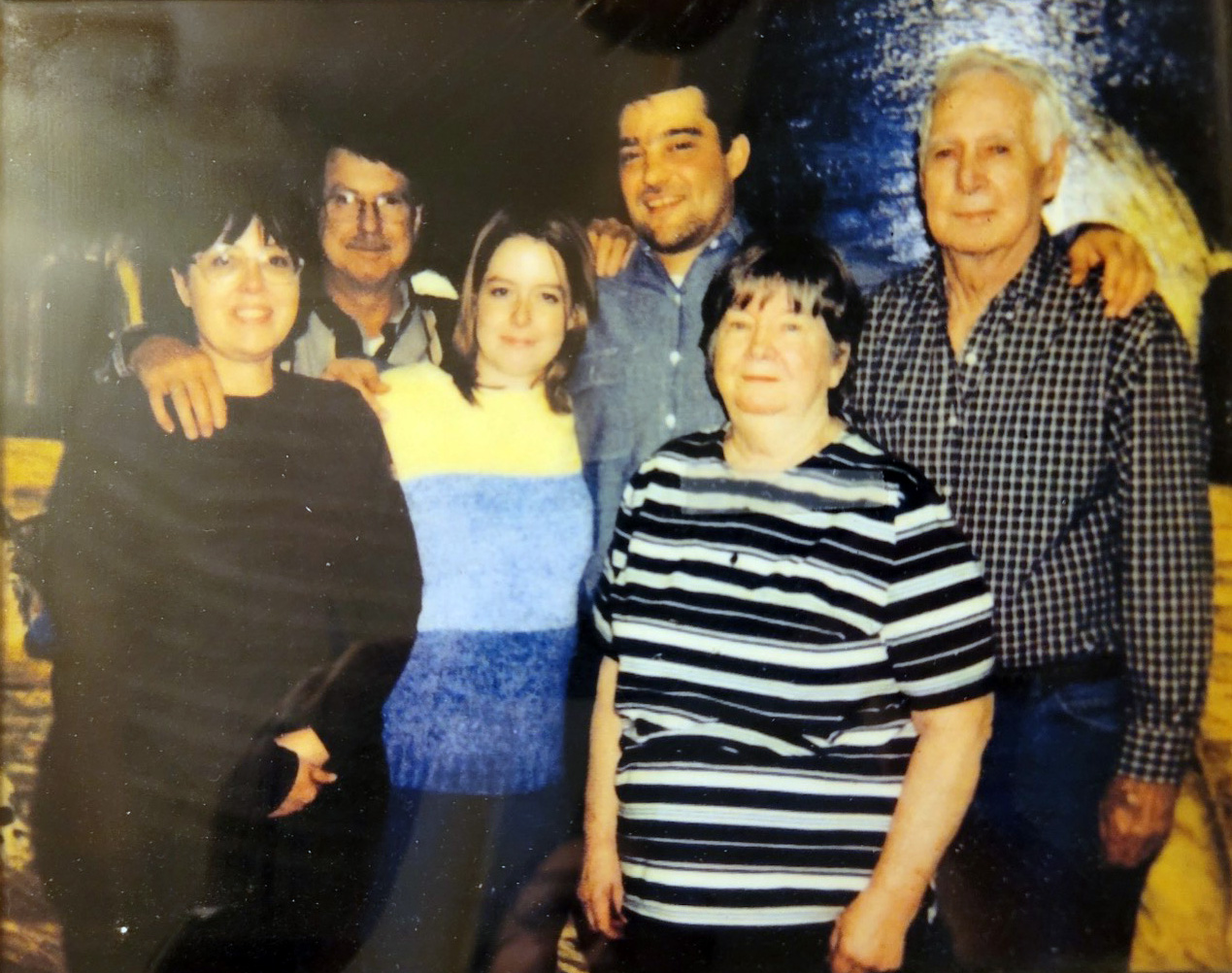 Group of six people standing together with their arms around each other.