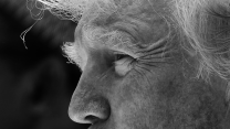 A tightly cropped black-and-white photograph of Donald Trump's face from the area just below his nose to his forehead. In the photo, as he looks to the left, you can see the wrinkles around his left eye, and the wisps of hair that make up his eyebrows and the strands of hair on his head.