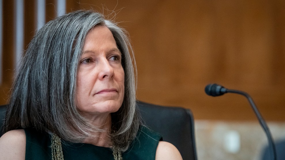 A woman with grey hair looks bored while sitting in front of a microphone.