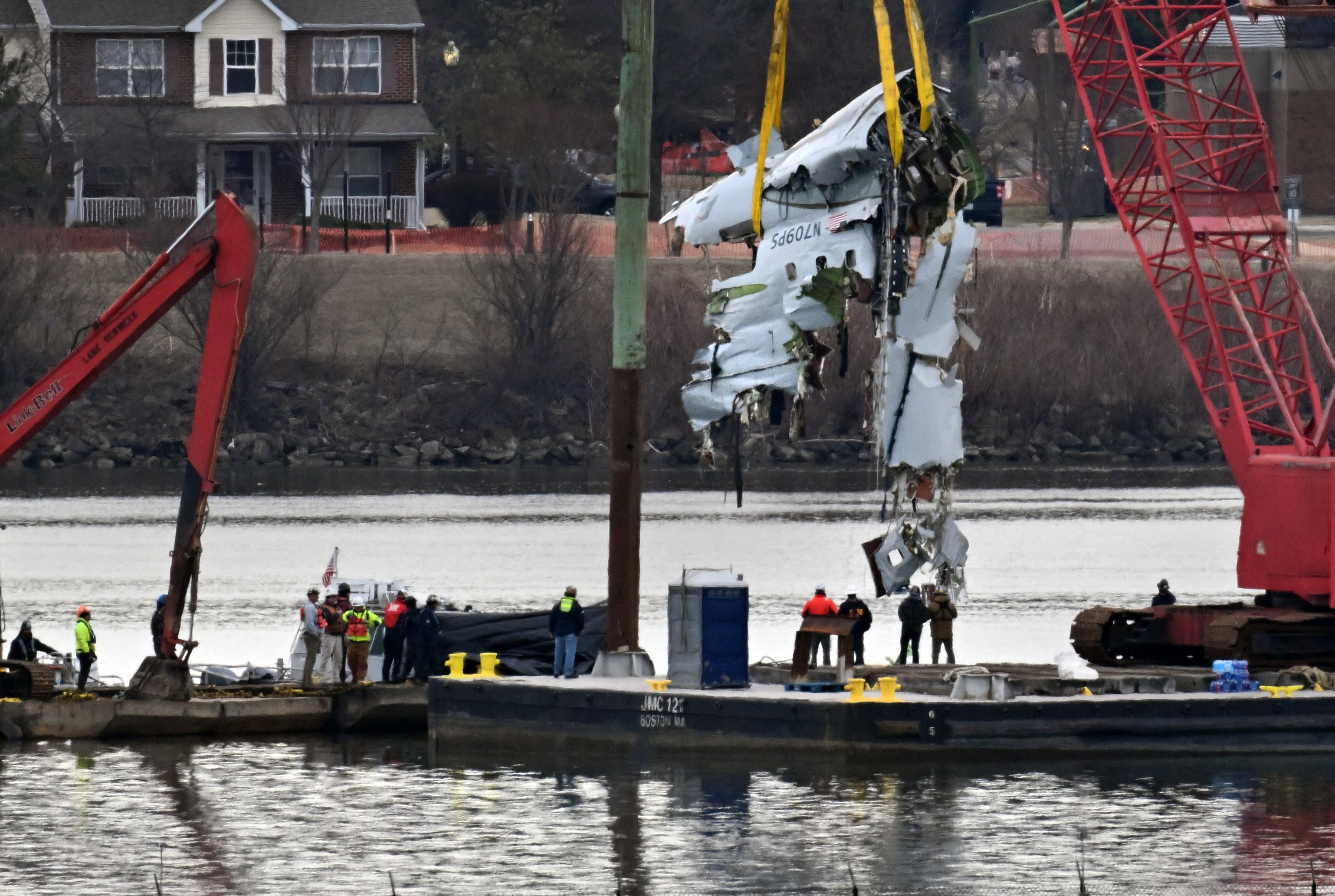Plane crash wreckage being lifted from a river.