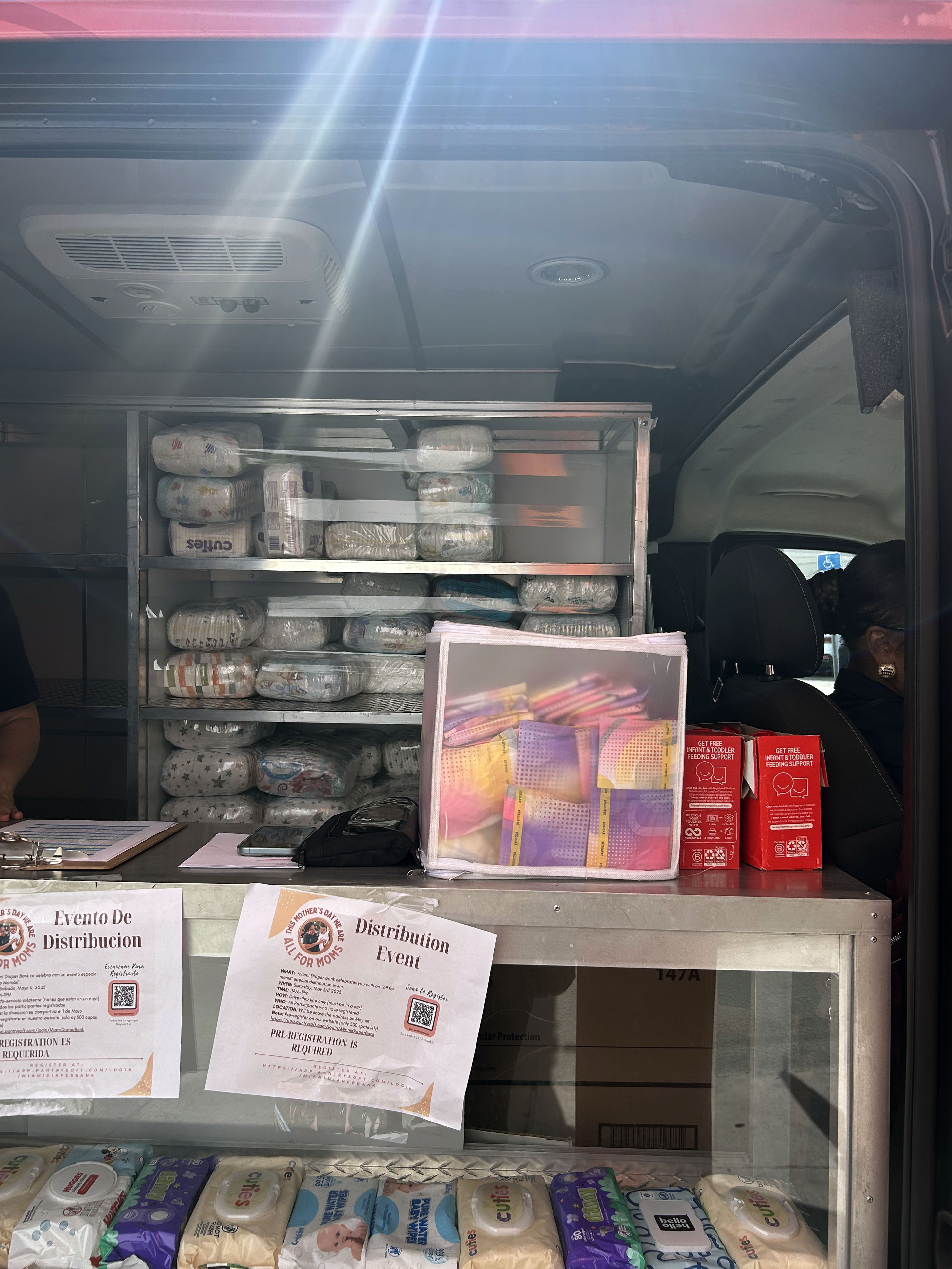 Diapers and other supplies stacked in the back of a van.
