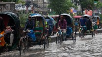 Cyclists pull rickshaws in waterlogged streets.