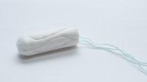 Close up of a tampon on a pale blue background.