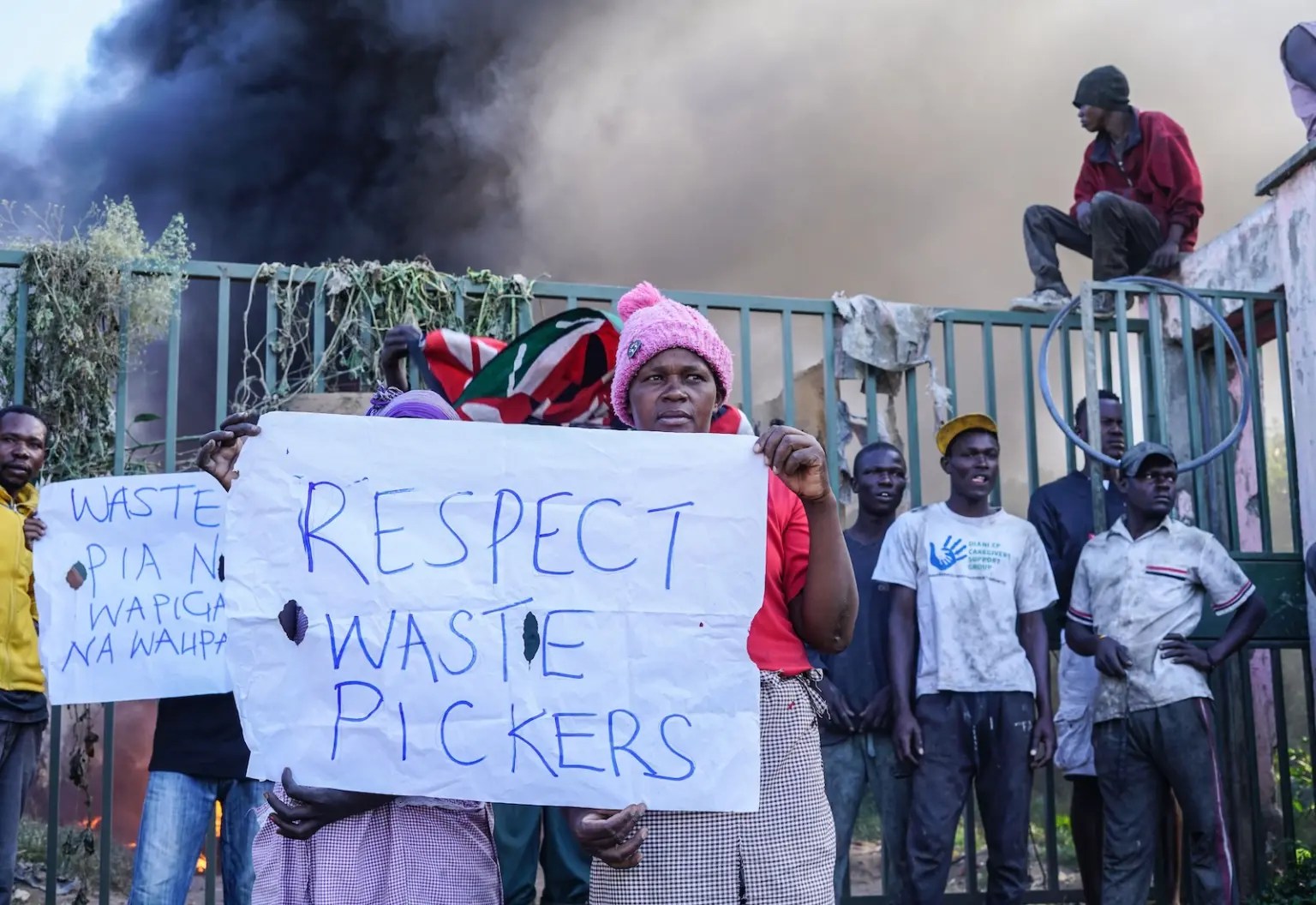 Workers hold a sign that says "respect waste pickers."