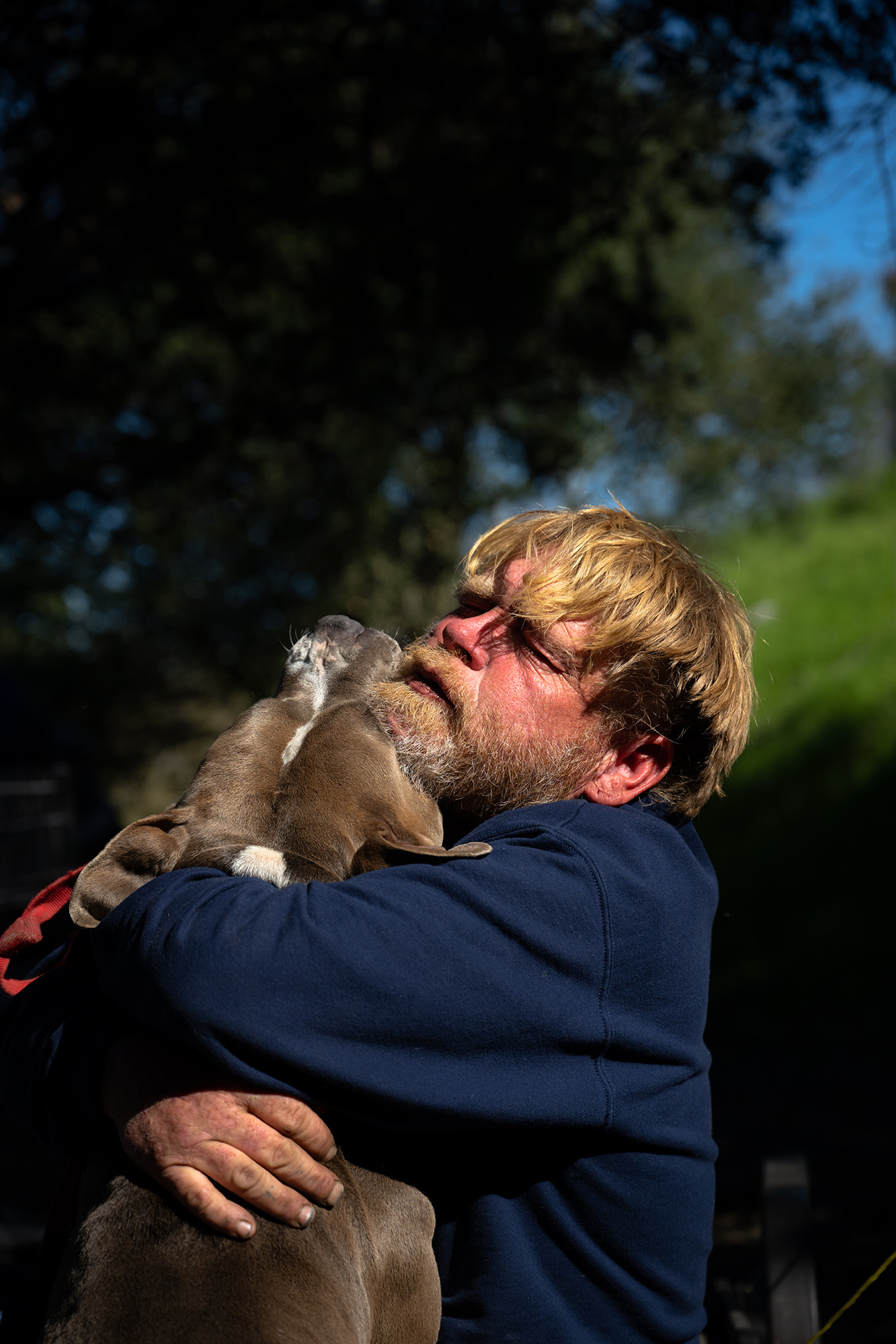 Man with a beard hugging a dog.