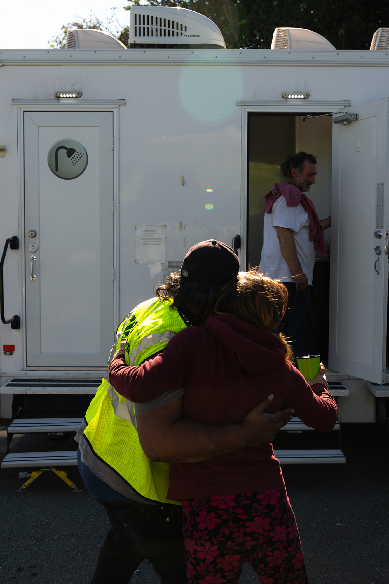 Two people hugging in front of a mobile showering trailer.