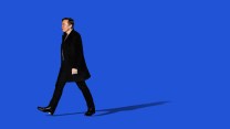 A photo illustration of Elon Musk walking away and smiling against a flat blue background