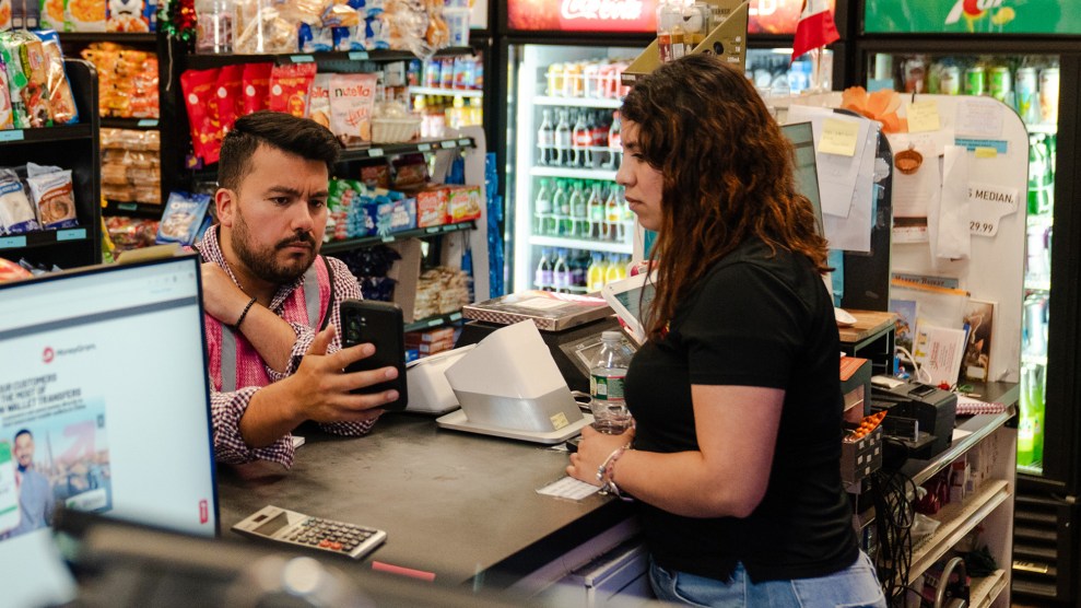 Man in a grocery store showing his phone to clerk.