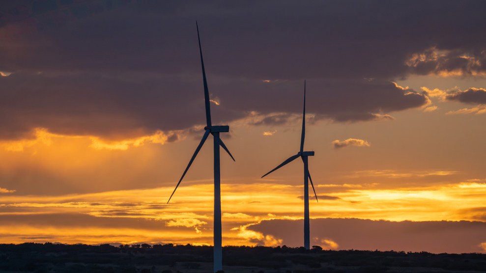 Two wind turbines in front of a sunset