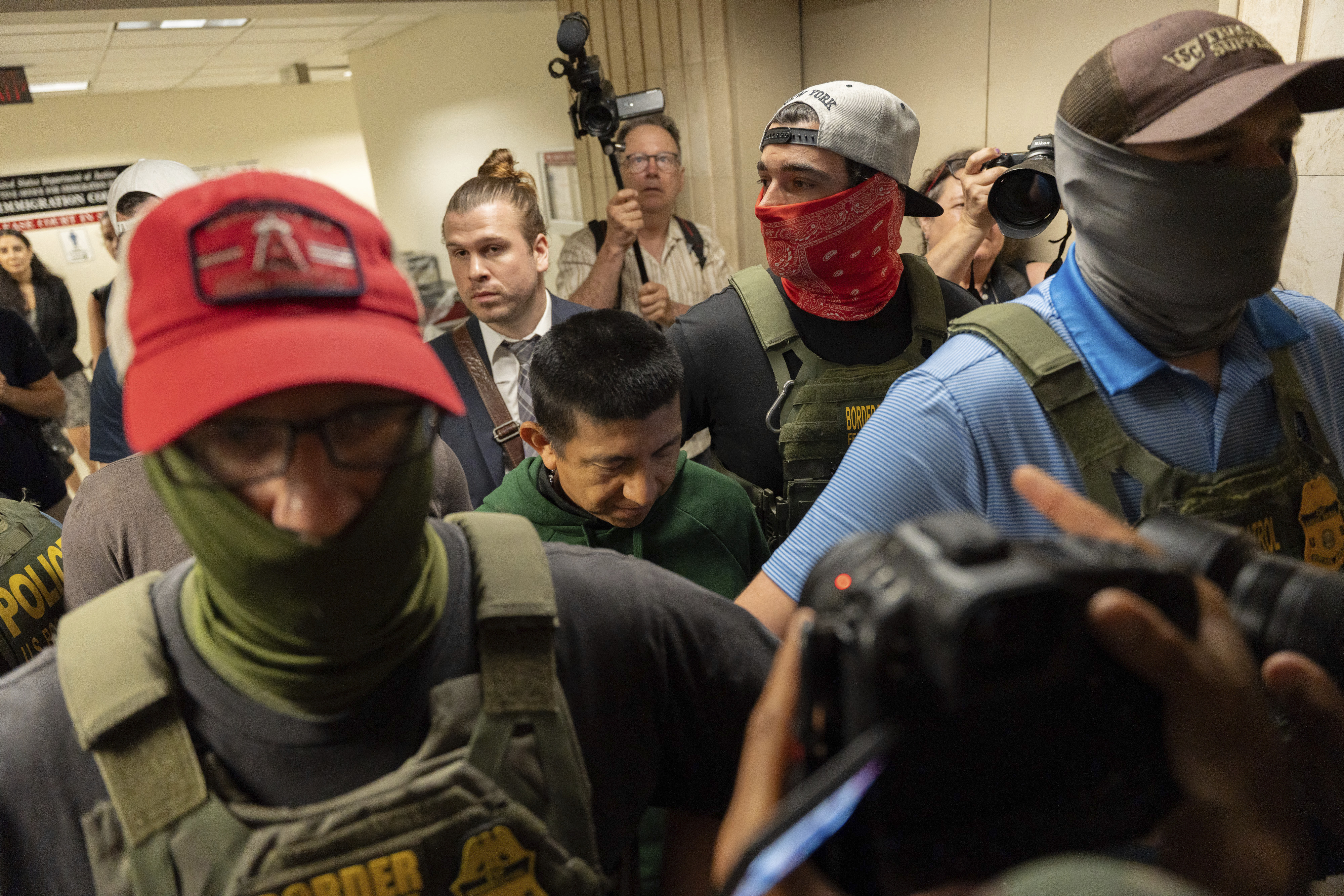 Immigration and Customs Enforcement (ICE) agents dressed casually in caps and jeans and face masks arrest noncitizens leaving court.