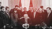 Donald Trump sitting behind his desk in the Oval Office with male and female pastors of various ages praying. Everyone's heads are bowed and eyes are closed.