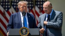 Trump speaking at a podium outside the White House with Dr. Phil to his left, looking at him adoringly.