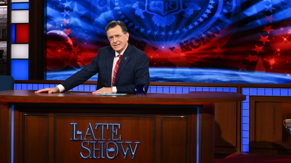 Colbert sits at his desk.