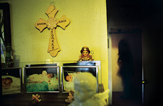 A wooden cross made by a friend hangs in one of the Romero household's two shrines to baby America, who died at five months.
